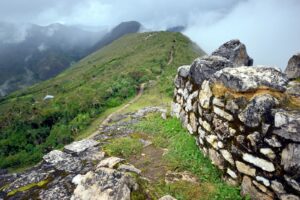 Muralla de piedra de la fortaleza de Kuélap con montañas cubiertas de vegetación y nubes al fondo